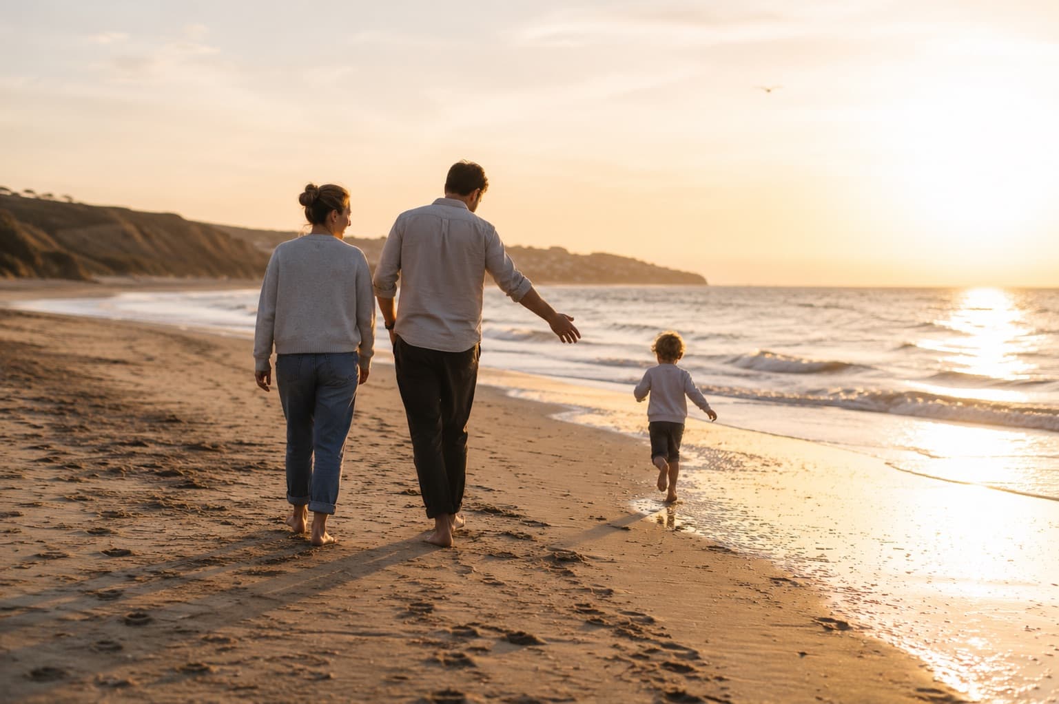 A family walking together along a beach at sunset